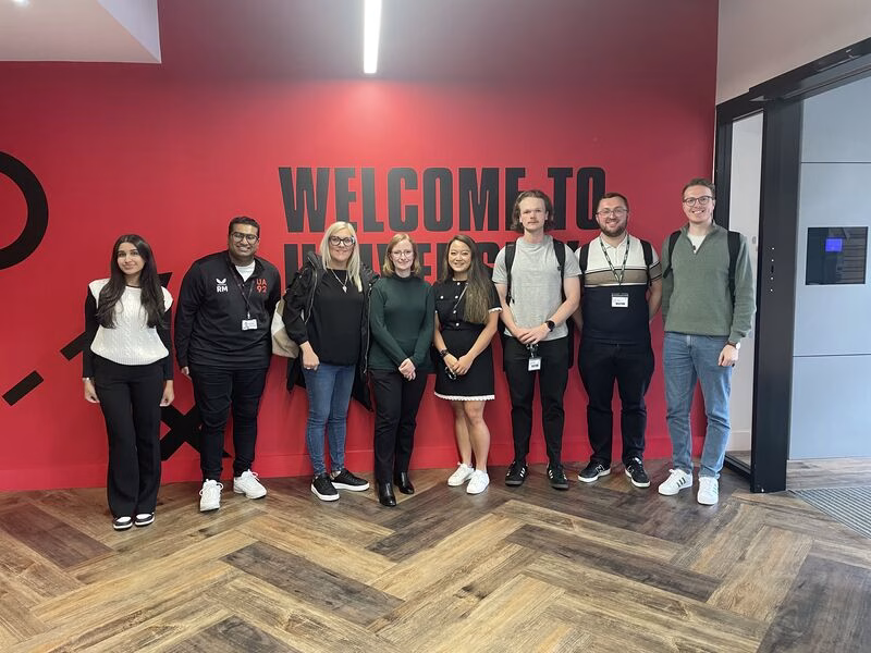 EY Colleagues stood in front of welcome sign at UA92's business school