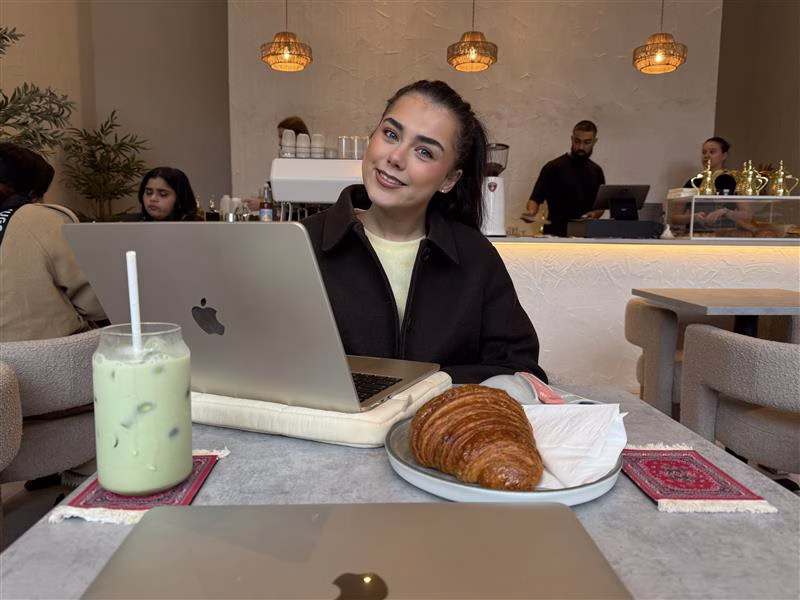 Saffron sat in a cafe with a drink and a pastry